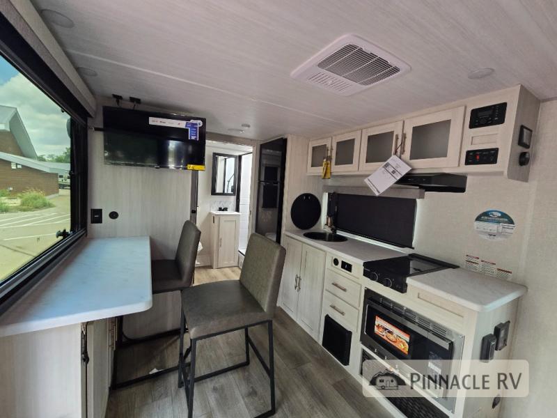 Forest River RV R Pod RP-197 travel trailer galley kitchen and bar with chairs. There's an overhead TV and a rear bathroom.