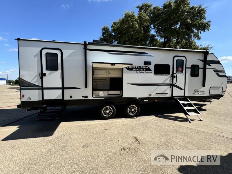 Coachmen RV Northern Spirit Ultra Lite 2963BH travel trailer set up on dealer's lot with dual entry doors and an outdoor kitchen.