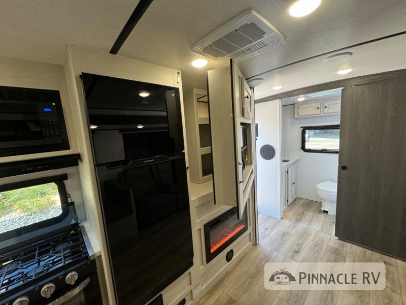 Coachmen RV Northern Spirit Ultra Lite 2557RB interior with an entertainment center with storage behind it, a bathroom, and a kitchen.